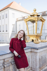 a lady wears a red tweed jacket with a matching skirt